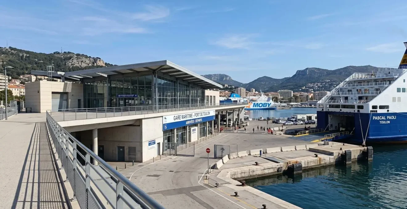 Vue large d'un terminal ferry moderne dans un port méditerranéen avec architecture portuaire contemporaine et ciel bleu lumineux
